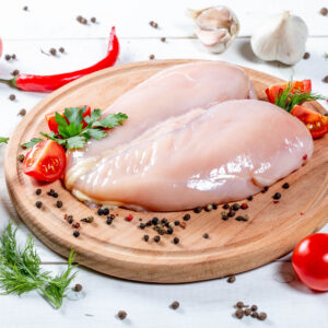 skinless chicken fillet with a set of spices, chili, tomatoes and garlic on the kitchen board