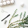 Flat lay of eggs, greenery, and tools for creative Easter decorations. Perfect for DIY enthusiasts.